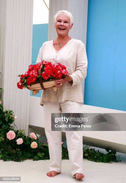 Dame Judi Dench poses with a trug of 'Drama Queen' roses while attending the press preview at the Hampton Court Palace Flower Show at Hampton Court...