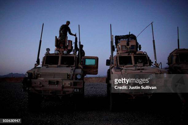 Army soldiers with a route clearance unit from 3rd Platoon, 123rd Engineer Company, 105th Engineer Battalion take a gun down from the top of an MRAP...