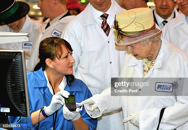 Queen Elizabeth II, wearing a white protective coat , is shown a new product, at the final testing before packaging test area during her tour of the...