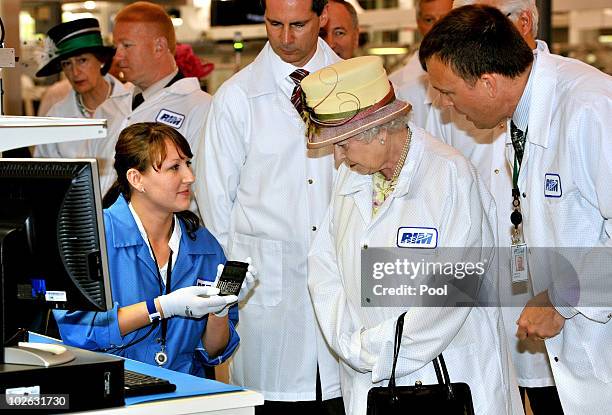 Queen Elizabeth II, wearing a white protective coat , is shown a new product, at the final testing before packaging test area during her tour of the...