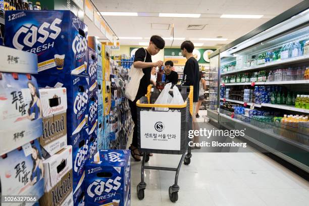 Customer puts a bottle of Oriental Brewery Co. Cass Fresh beer into a shopping cart at an E-Mart Inc. Store in Seoul, South Korea, on Friday, Aug....