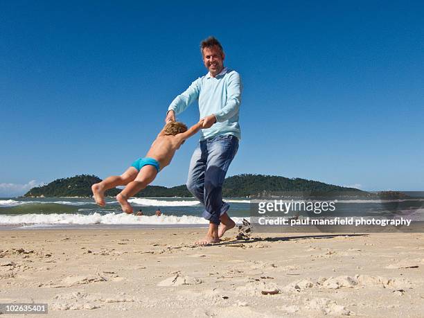 father playing with his son on sandy beach - florianopolis foto e immagini stock