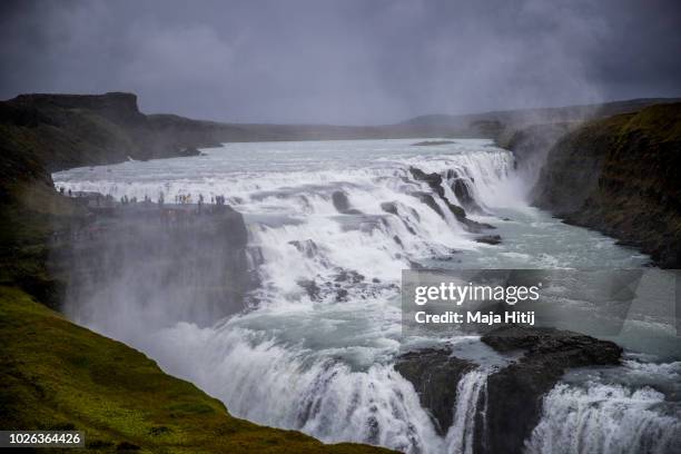 Visitors stand near Gullfoss waterfall located in the canyon of the Hvita river in southwest Iceland on August 31, 2018 near Blaskogabyggo, Iceland.