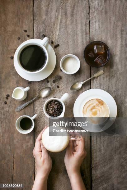 conceptual flat lay coffee in cups. - hand resting on wood stock-fotos und bilder