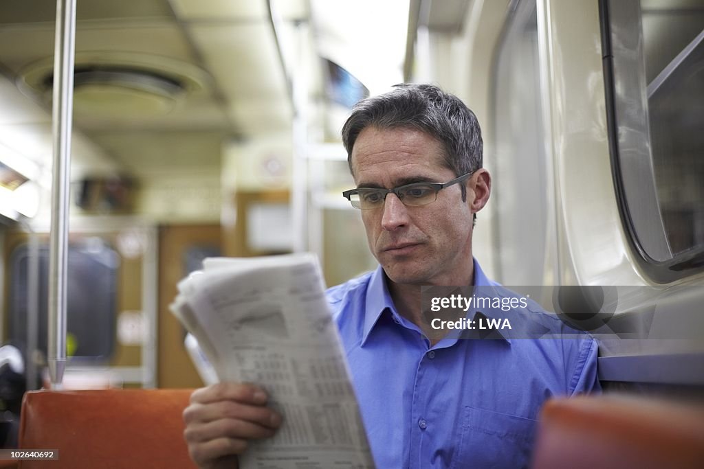 Man Reading Newspaper On Subway
