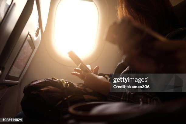 asian man hand holding smart-phone start up working  on board of airplane near window seat - airplane phone stock-fotos und bilder