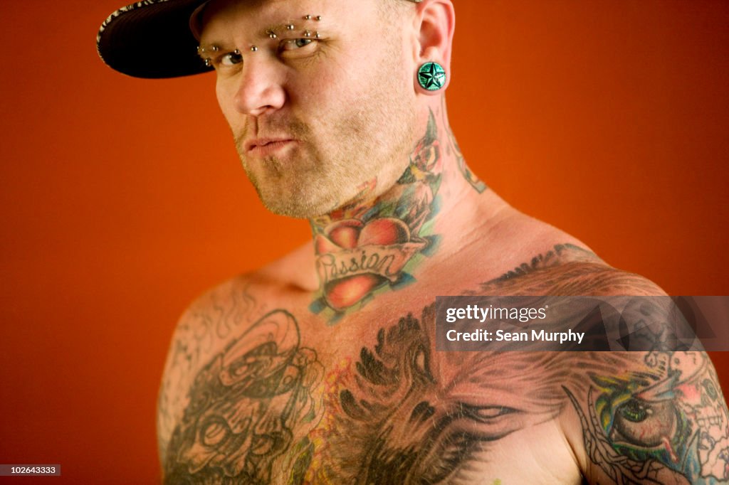 Tattooed man against red wall