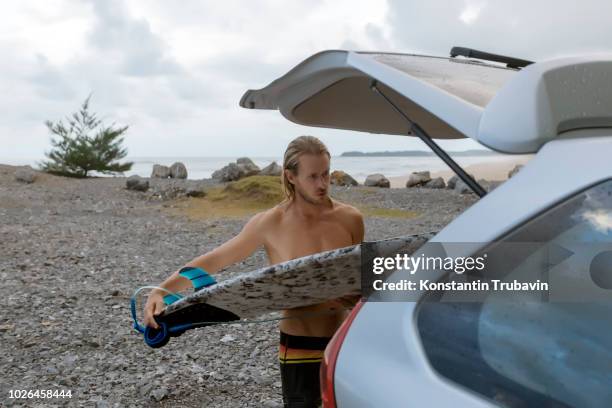 surfer putting surfboard in trunk of car - banda aceh stock pictures, royalty-free photos & images