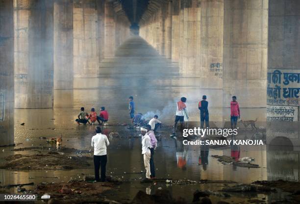 Indian people cremate a body near the flooded River Ganges under Shastri bridge at Daraganj ghat, in Allahabad on September 3 as water levels of the...