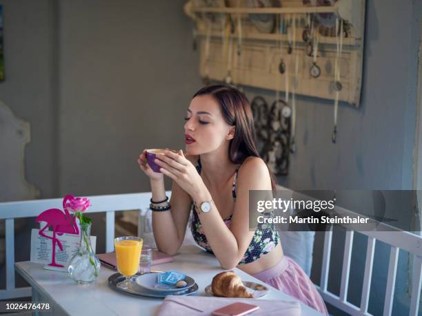 frau sitzt im café bei frühstück mit kaffee in der hand - frau essen stock pictures, royalty-free photos & images