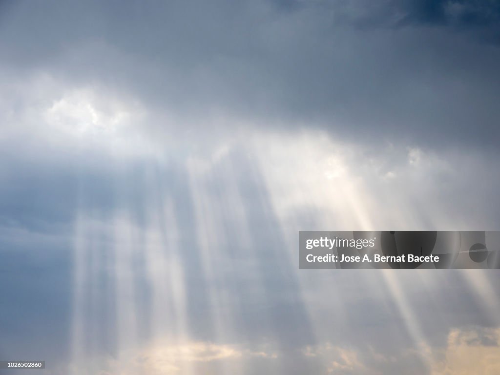Full frame of the low angle view of white and gray clouds of rain and storm with sunbeams. Valencian Community, Spain