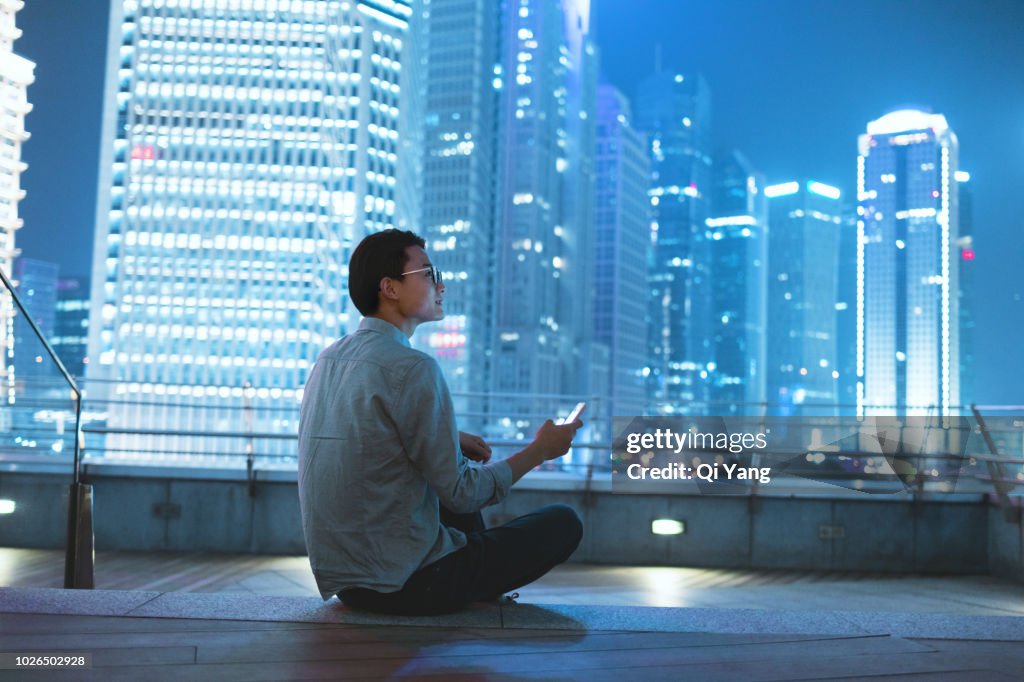 Young businessman looking at smartphone on the roof