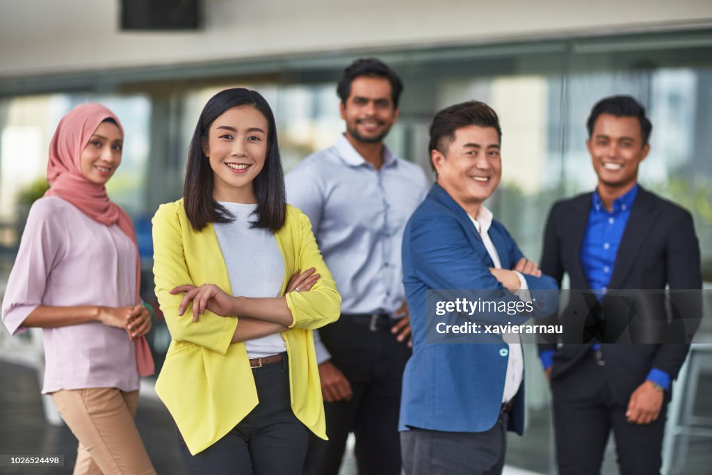 Businesswoman standing arms crossed with team