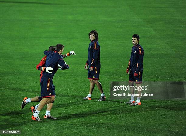 Cesc Fabregas of Spain stands smiling with his teammate Carles Puyol as goalkeeper Victor Valdes and Gerard Pique joke around during a training...