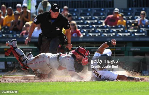 Jose Osuna of the Pittsburgh Pirates slides safely into home plate past Tucker Barnhart of the Cincinnati Reds in the seventh inning during the game...