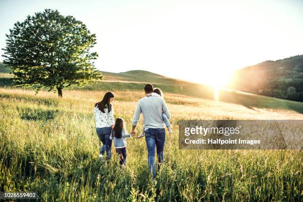 happy family with two small children walking outside in spring nature at sunset. rear view. - beautiful wife pics fotografías e imágenes de stock