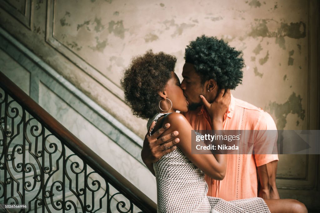 Young Couple kissing on steps against wall, Havana, Cuba