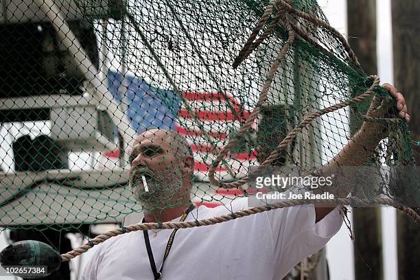 Clyde Perez secures the shrimp nets on the shrimping boat he works on as they prepare to depart from Rigolets marina on July 6, 2010 in Greens Ditch,...