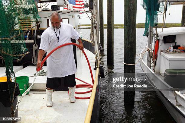 Clyde Perez cleans off the deck of the shrimping boat he works on in preparation to depart from Rigolets marina July 6, 2010 in Greens Ditch,...