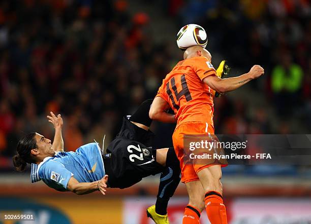 Martin Caceres of Uruguay kicks Demy De Zeeuw of the Netherlands during the 2010 FIFA World Cup South Africa Semi Final match between Uruguay and the...