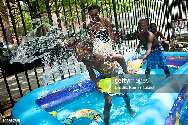 The Richardson family of Brooklyn play in an inflatable pool near their apartment on July 6, 2010 in the Brooklyn borough of New York City. The...