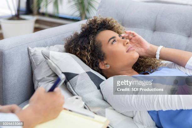 distraught therapy client lays on couch - hypnosis stock pictures, royalty-free photos & images