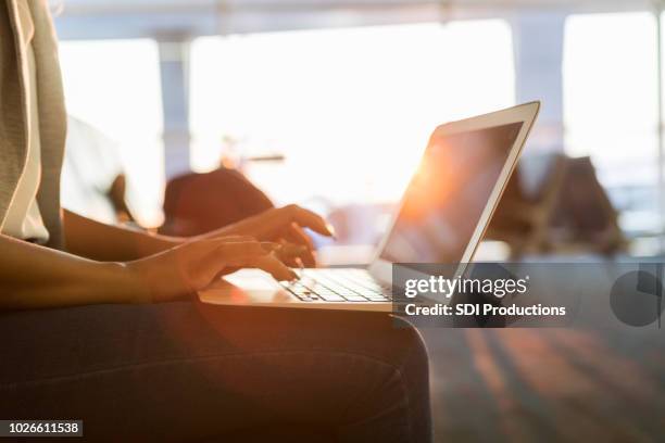 young businesswoman uses laptop in airport - white collar worker dawn light stock pictures, royalty-free photos & images