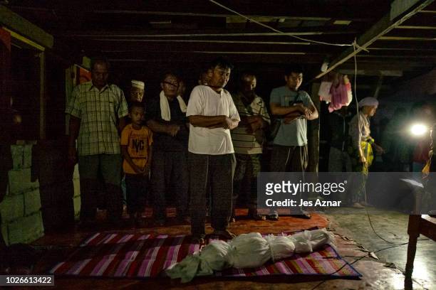Fighters and family members offer prayers to the body of Jahira Ibrahim Makmud after drowning from a fishpond near their makeshift house on August 26...
