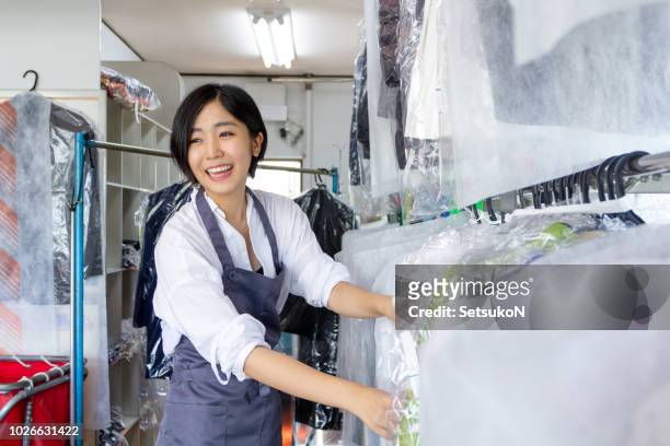 亞洲乾洗清潔工在檢查衣服時說話 - dry cleaner 個照片及圖片檔