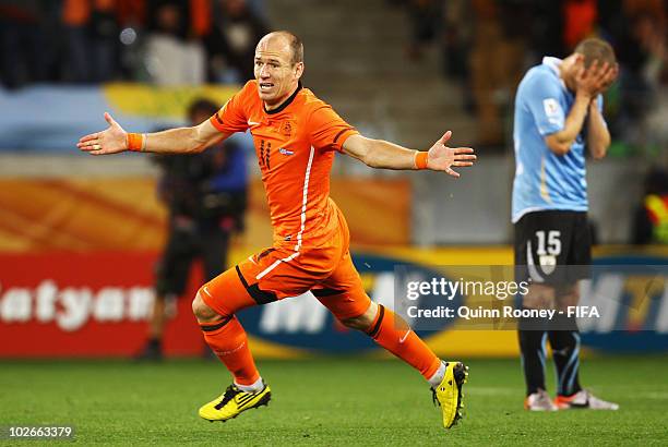 Arjen Robben of the Netherlands celebrates scoring the third goal as Diego Perez of Uruguay stands dejected during the 2010 FIFA World Cup South...