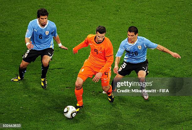 Robin Van Persie of the Netherlands in action against Mauricio Victorino and Maximiliano Pereira of Uruguay during the 2010 FIFA World Cup South...
