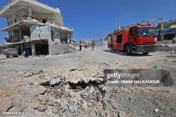 Picture taken on September 4, 2018 shows a fire engine drives through a damaged road after a reported Russian air strikes in the rebel-held town of...