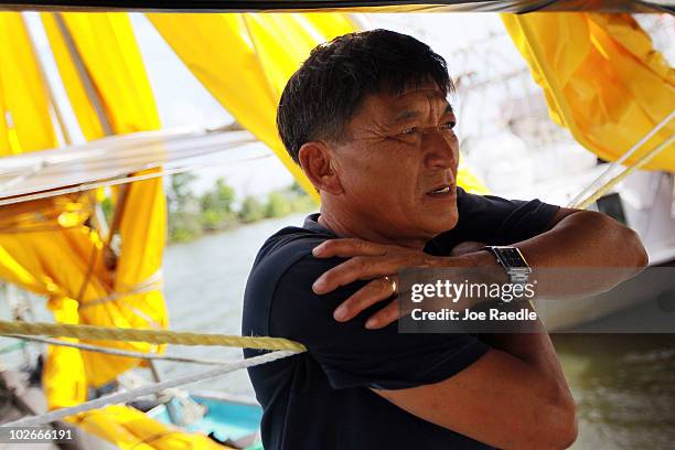 Phung Pham, who is a deck hand on a boat hired by BP to help with oil skimming operations, stands on the boat after being forced to stay in due to...