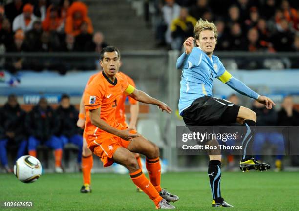 Diego Forlan of Uruguay eyes the ball with Giovanni van Bronckhorst of the Netherlands during the 2010 FIFA World Cup South Africa Semi Final match...