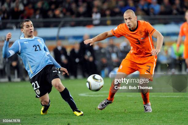 John Heitinga of the Netherlands handles the ball against Sebastian Fernandez of Uruguay during the 2010 FIFA World Cup South Africa Semi Final match...