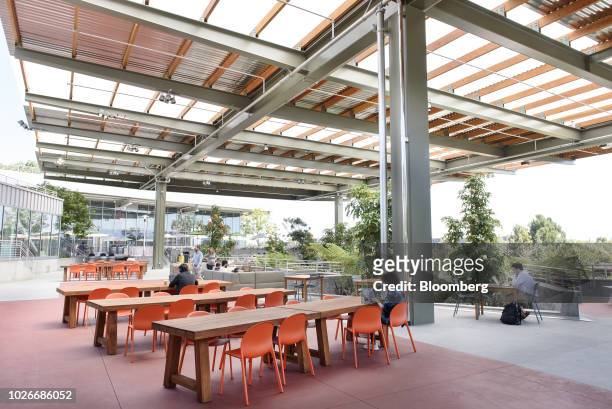 Employees work on laptop computers in an outdoor spaced, referred to as the Bowl, at the new Facebook Inc. Frank Gehry-designed MPK 21 office...
