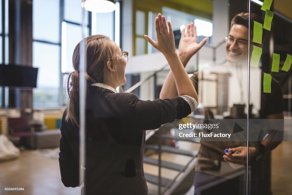 Colleagues high-fiving at work