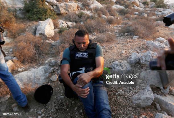 Issam Rimavi, a photojournalist of the Turkey's Anadolu Agency, holds his right knee as he gets injured by the intervention of Israeli forces while...