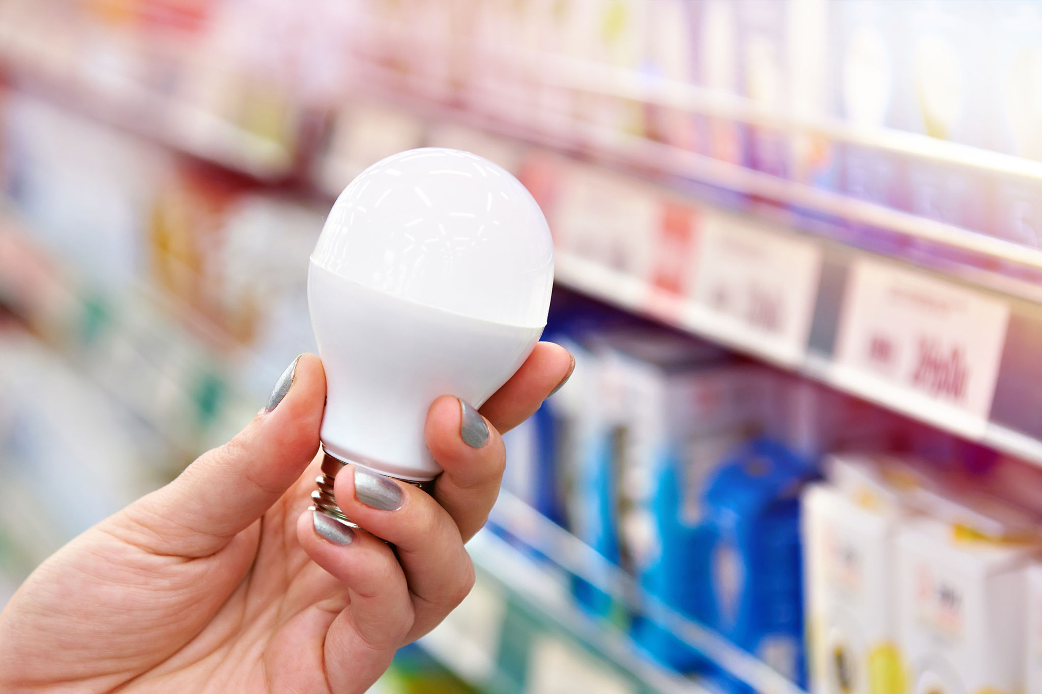 Energy saving LED lamp in hands of buyer at store Energy saving LED lamp in hands of buyer at store