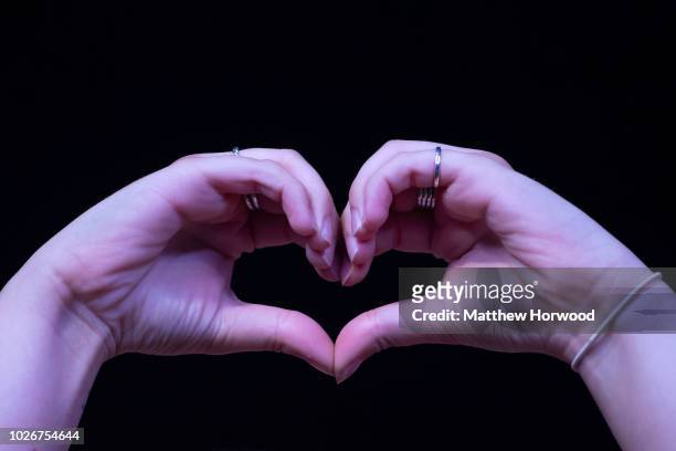 Woman holds her hands together in the air in the shape of a heart during the Pride Cymru Big Weekend on August 25, 2018 in Cardiff, Wales. Pride...