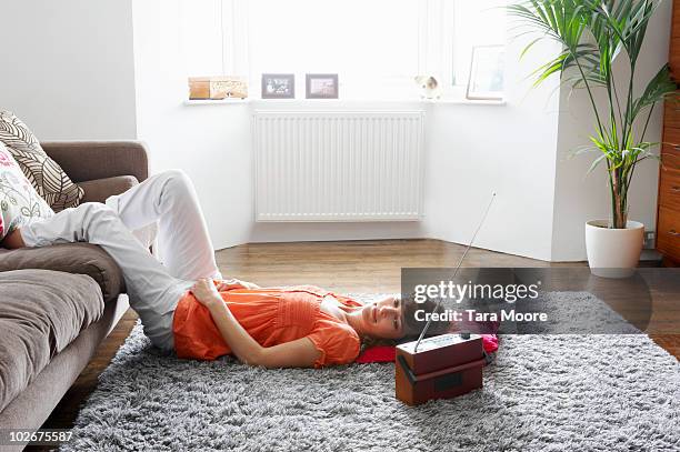 woman lying on carpet listening to music - poste de radio photos et images de collection