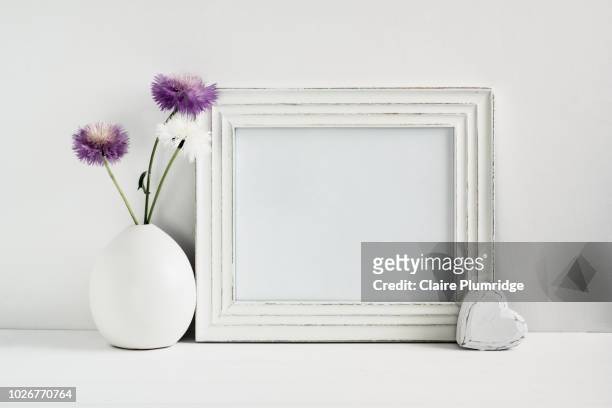 pastel - styled stock frame mock-up image with purple and white stokes asters in a white vase next to a blank white frame. - femininity photos stock pictures, royalty-free photos & images