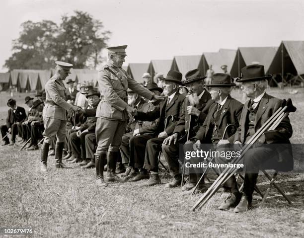American military commanders generals John Lejeune and Dion Williams shake hands with a seated line of elderly veterans, near the site of the Battle...