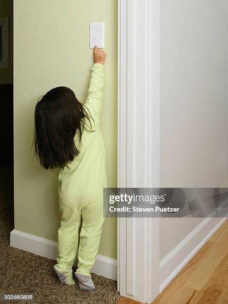 young girl reaching for light switch - trying on ストックフォトと画像