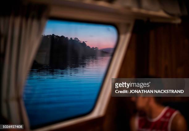 Participant looks out of a window as the ferry passes by an island on the way to the starting point of the OTILLO Swimrun competition from Sandhamn,...