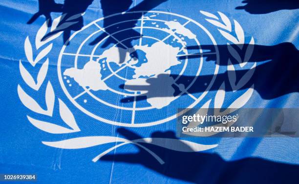 Palestinian school children raise the victory gesture over a UN flag during a protest at a United Nations Relief and Works Agency school, financed by...