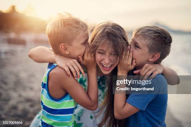 kinder, die spaß am strand sonnenuntergang - child whispering stock-fotos und bilder