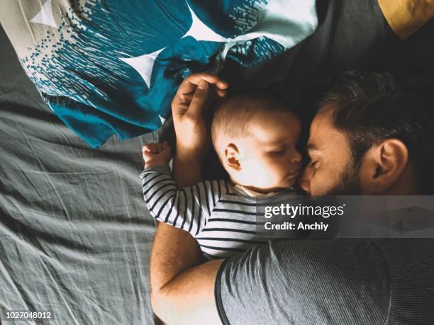 padre e hijo de dormir en la cama - new baby fotografías e imágenes de stock