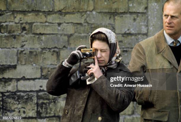 Queen Elizabeth ll takes photographs with her gold Rollei camera during a visit to the Badminton Horse Trials with Prince Philip, Duke of Edinburgh...
