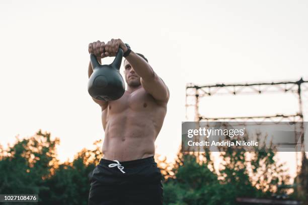 uomo atletico che fa swing russo nella natura al tramonto - kettlebell chest press foto e immagini stock
